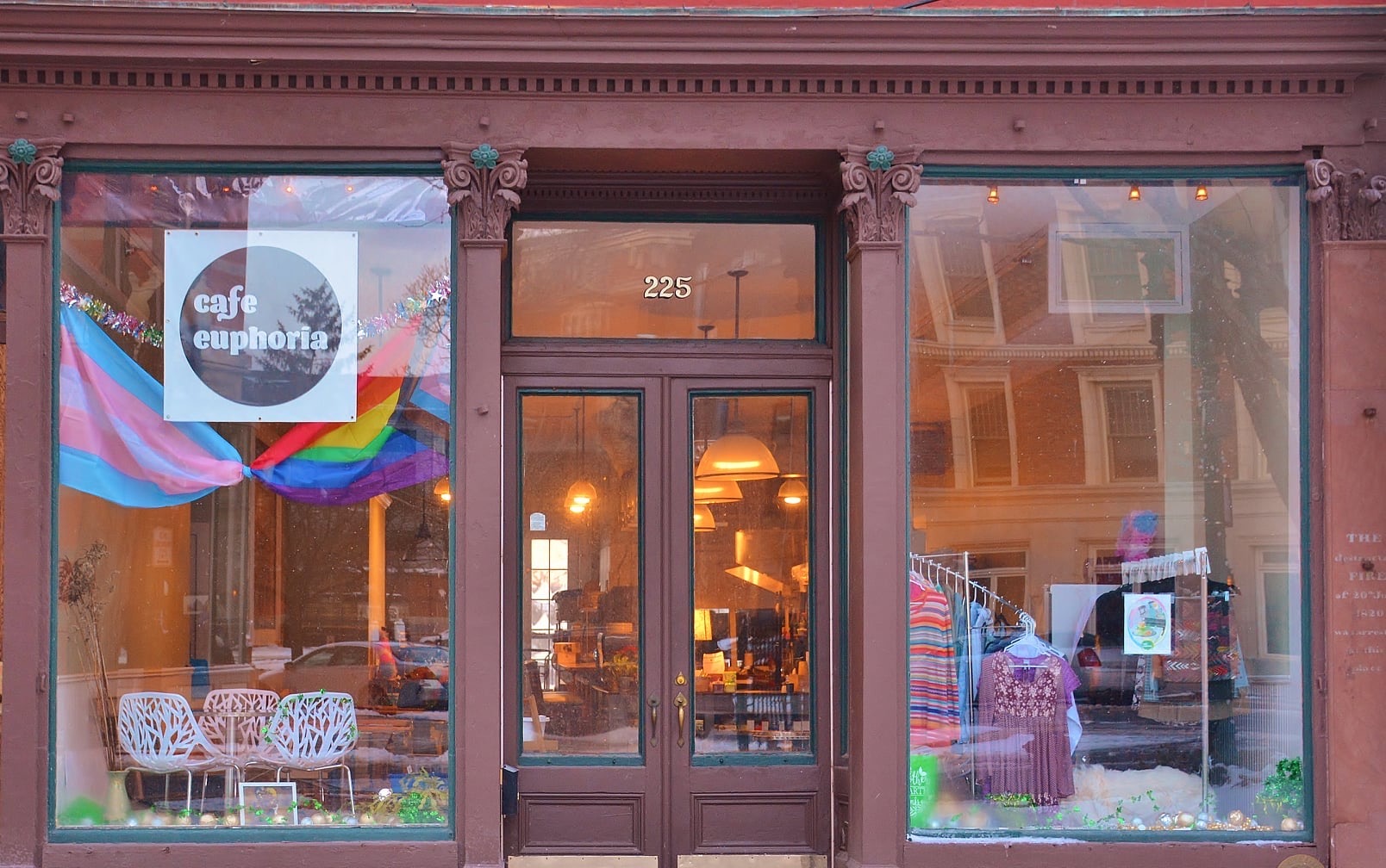 The exterior of Cafe Euphoria is situated on River Street in Troy. It features a burgundy facade and expansive windows that showcase the seating area and the front of the house.