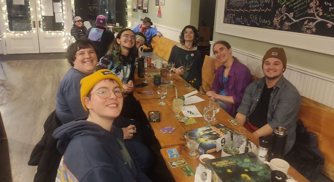 A group of people are sitting in the cafe playing board games on game night!
