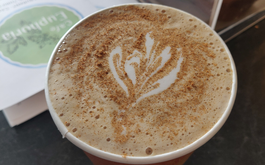 A latte with floral latte art in dusted cinnamon. 